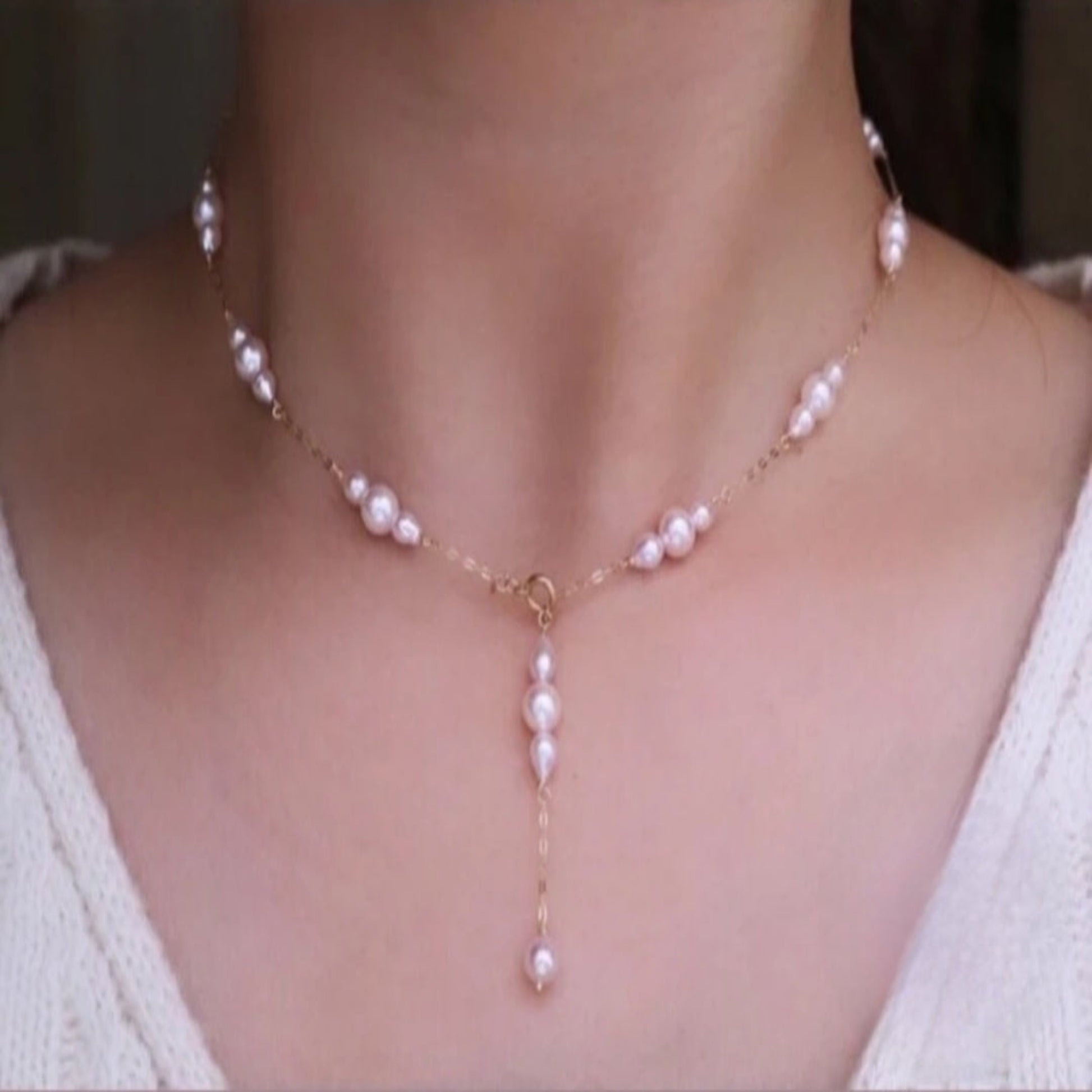 Pearl necklace on a person wearing a white top