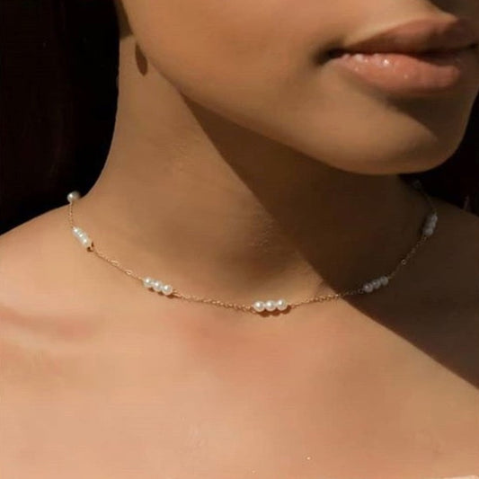 Close-up of a pearl necklace on a person's neck with a blurred background