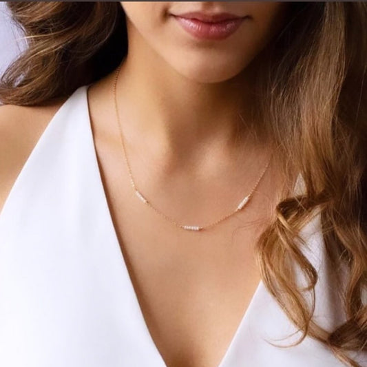 Close-up of a woman wearing a delicate gold necklace against a white background