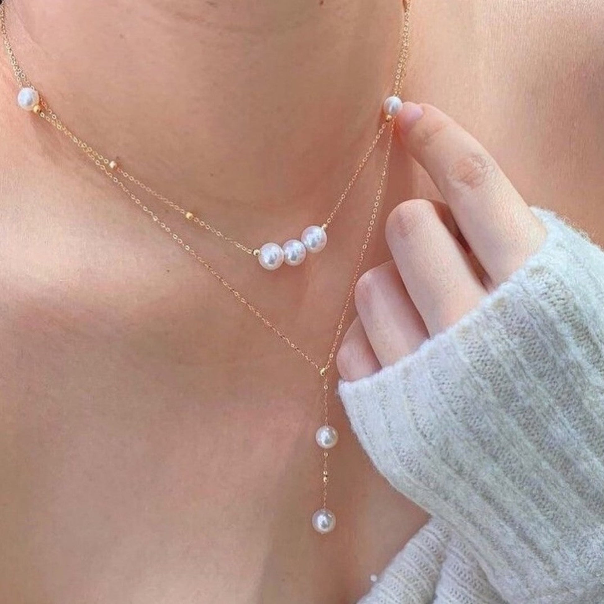 Pearl necklace with gold chain worn by a person, close-up shot.