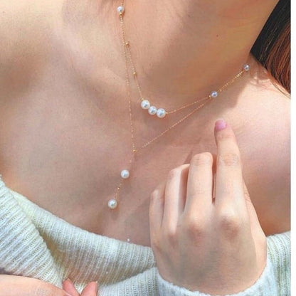 Pearl necklace being worn with a hand touching the chest