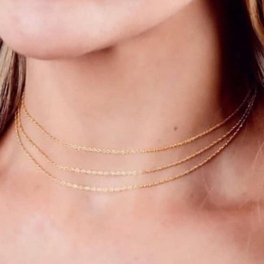 Close-up of a person wearing a delicate gold necklace.