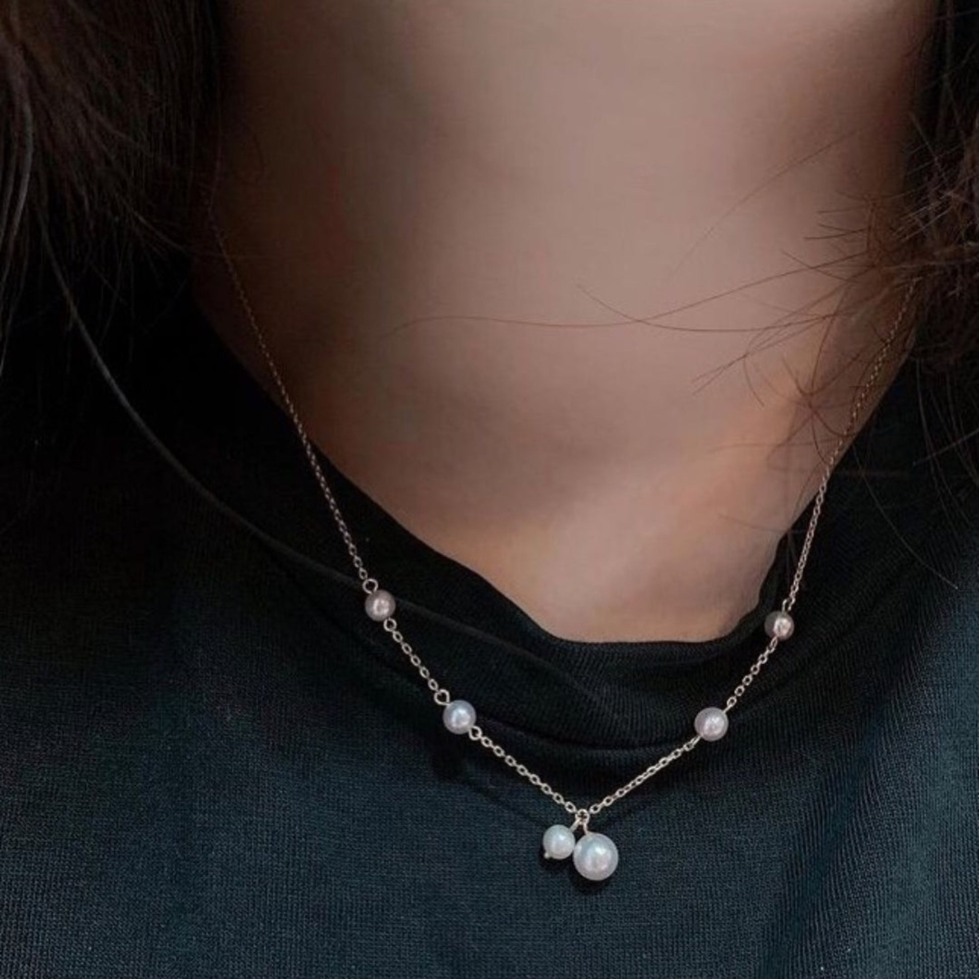 Pearl necklace worn by a person on a dark background