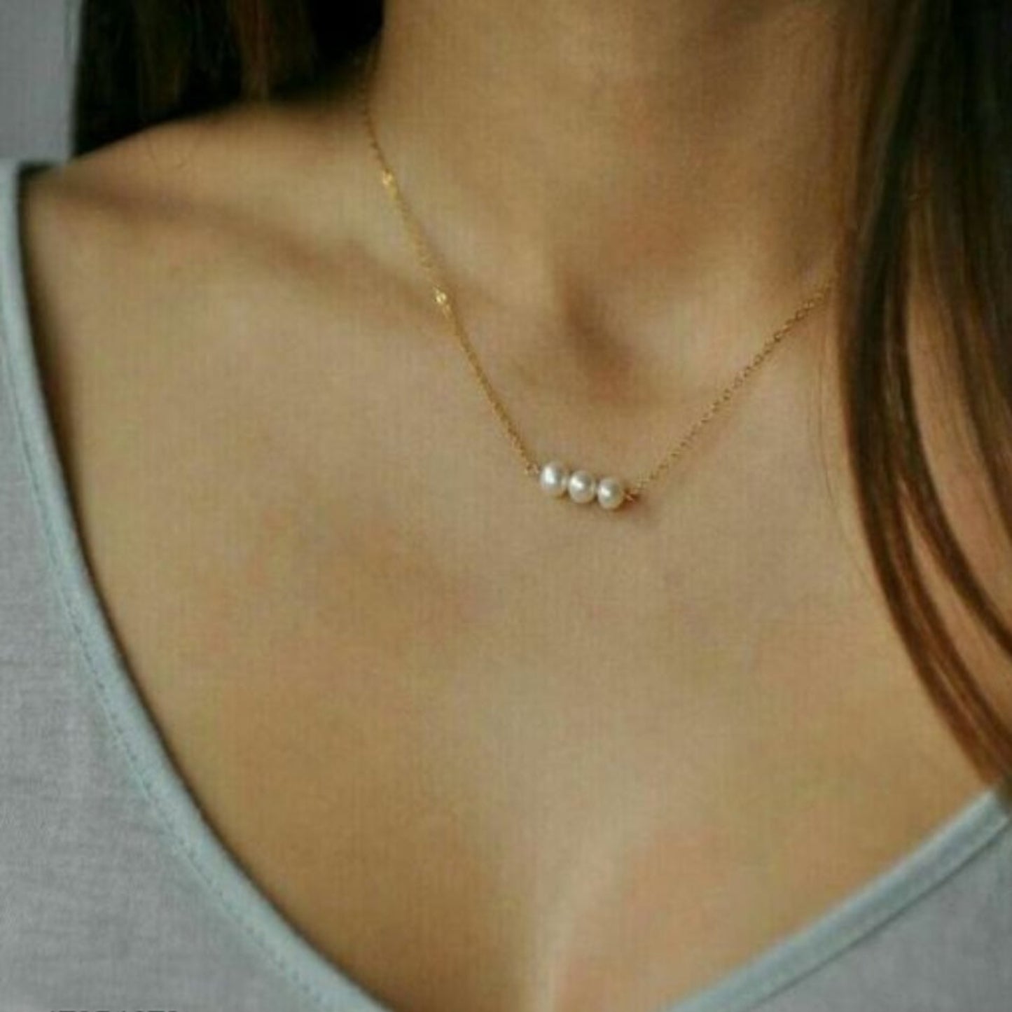 Pearl necklace worn by a person with a neutral background
