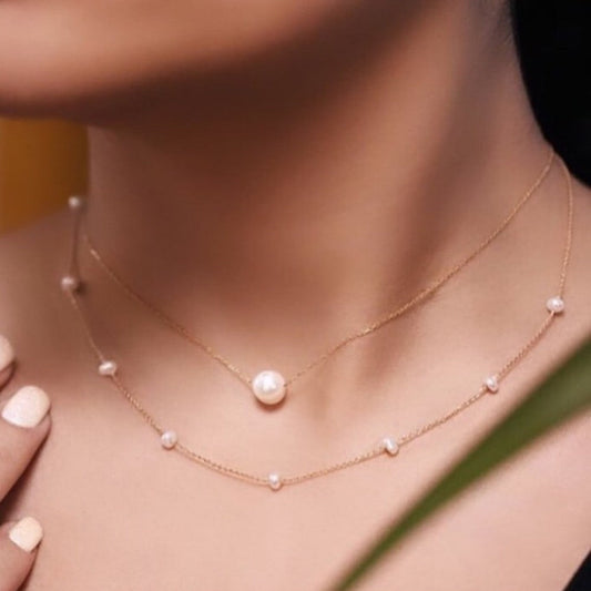 Gold necklace with pearls on a person's neck against a blurred background