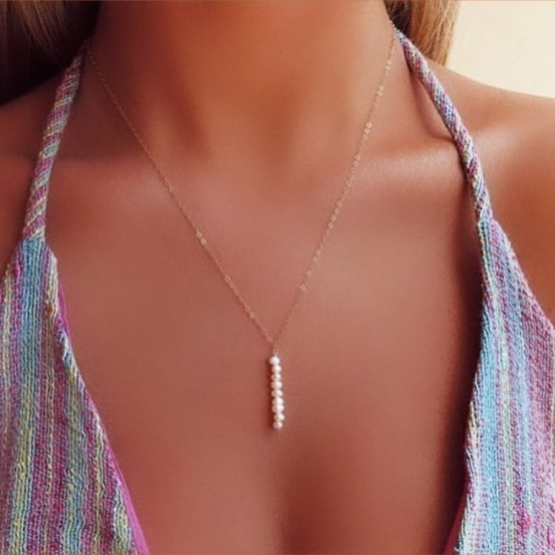 Necklace with a pendant on a person wearing a colorful top.