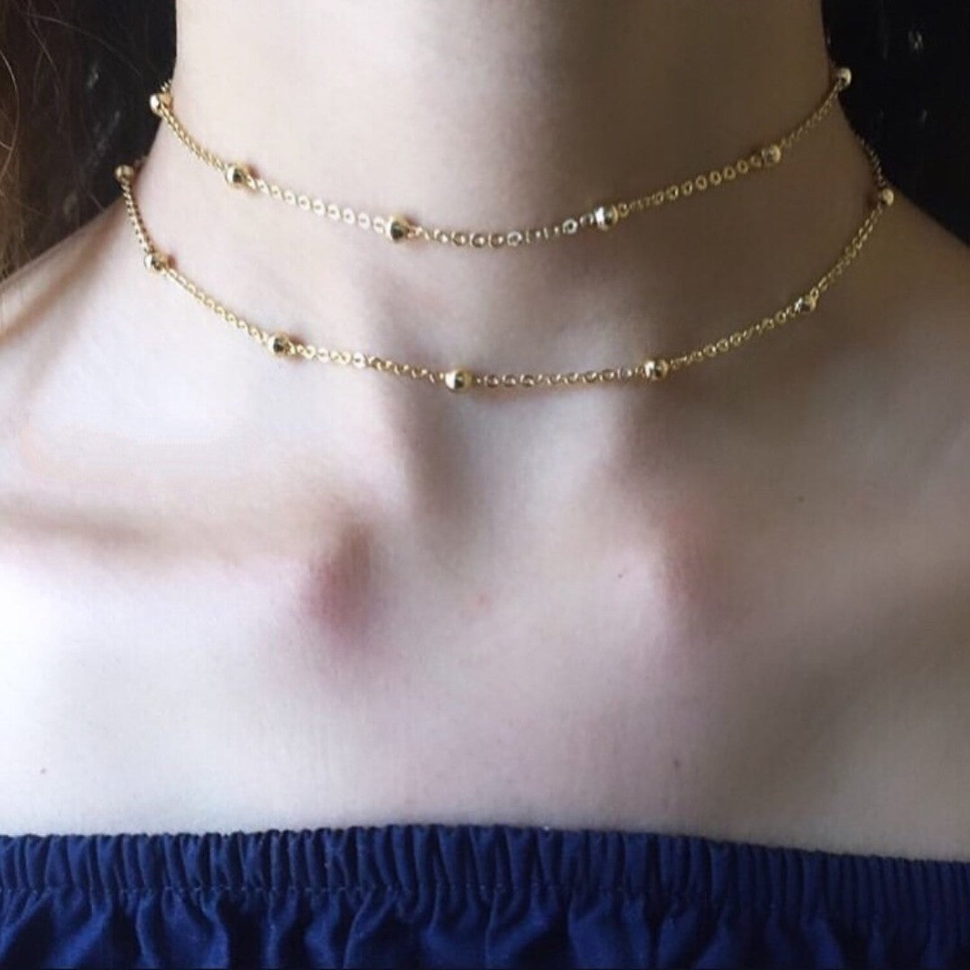 Gold necklace on a person's neck with a blurred background