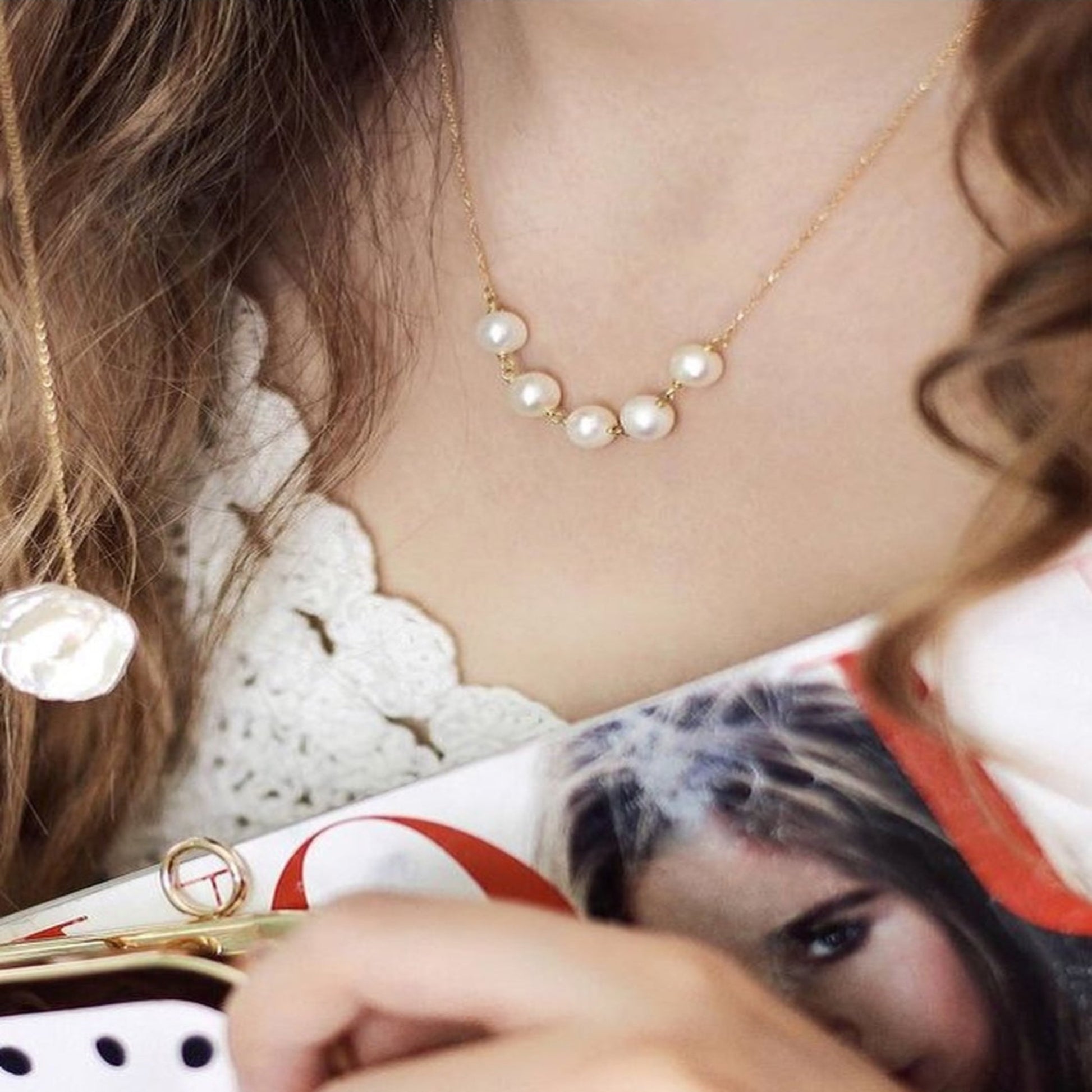 Close-up of a person wearing a pearl necklace with a blurred background