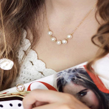 Close-up of a person wearing a pearl necklace with a blurred background