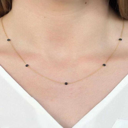 Necklace with black beads worn by a person on a white background