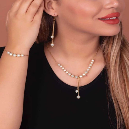 Woman wearing a pearl necklace, bracelet, and earrings on a beige background