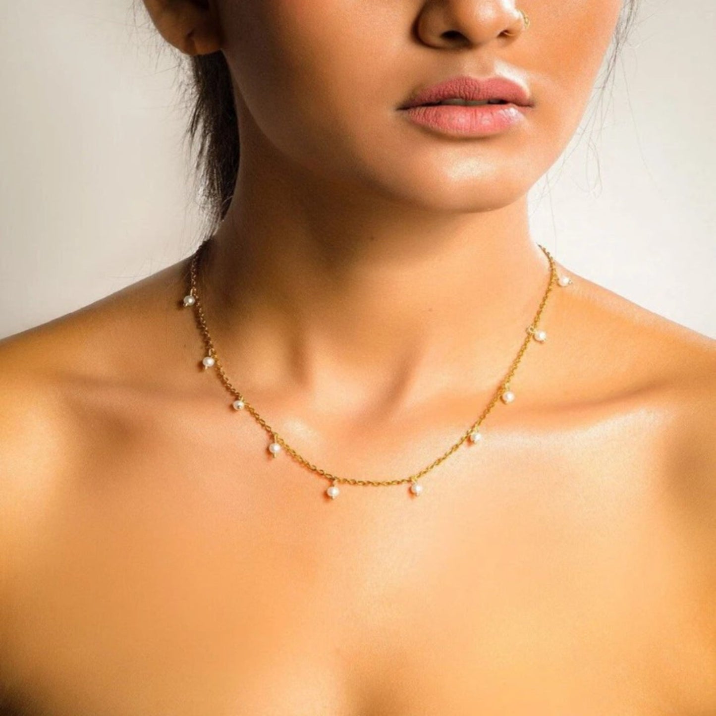 Close-up of a woman wearing a delicate gold necklace with small beads.