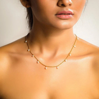 Close-up of a woman wearing a delicate gold necklace with small beads.