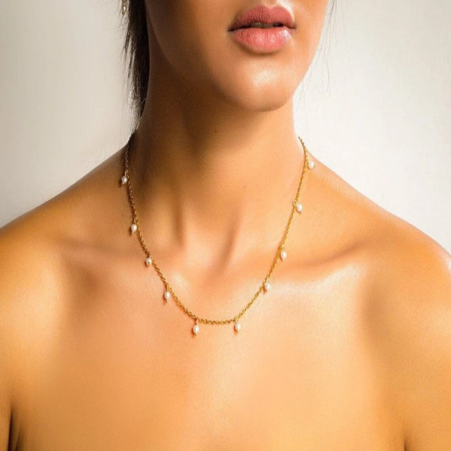 Close-up of a necklace on a person with a neutral background
