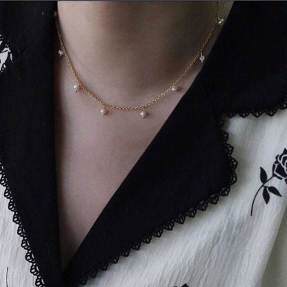 Pearl necklace worn by a person with a black and white outfit