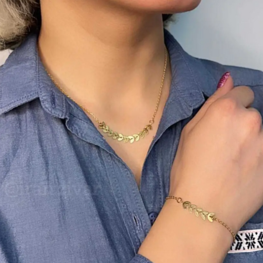 Person wearing a gold necklace and bracelet against a blue shirt.