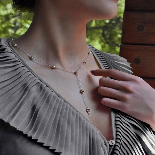 Necklace with small beads worn by a person in a natural setting