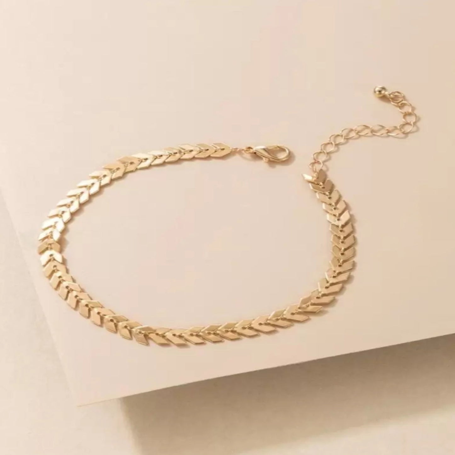 Gold chain bracelet on a beige background