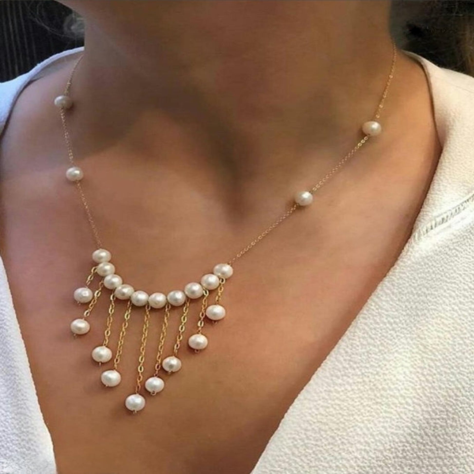 Pearl necklace with gold chain worn by a person