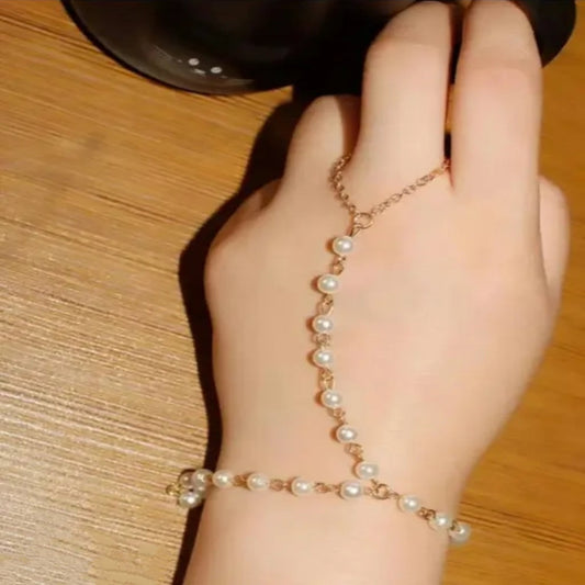 Hand wearing a pearl bracelet on a wooden surface