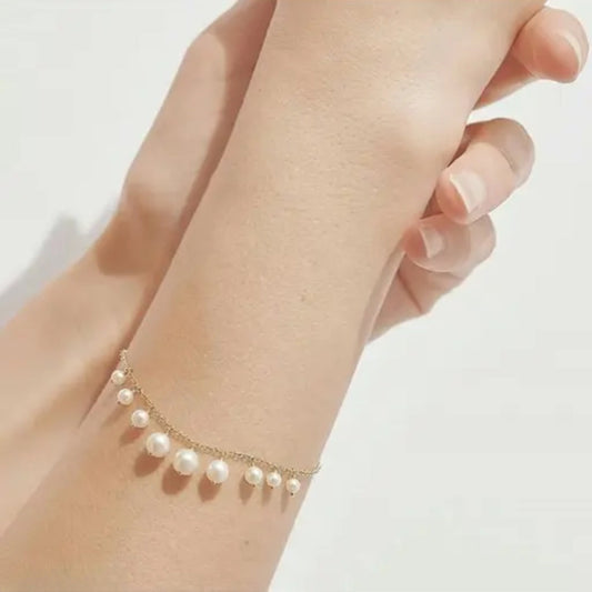 Pearl bracelet on a wrist with a plain background