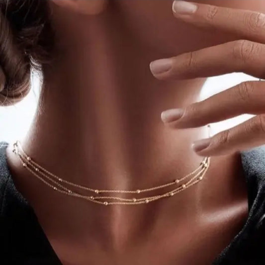 Close-up of a woman wearing a delicate gold necklace with a blurred background
