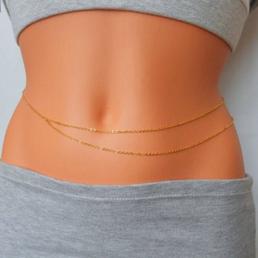 Gold chain belt on a person wearing gray pants against a light background