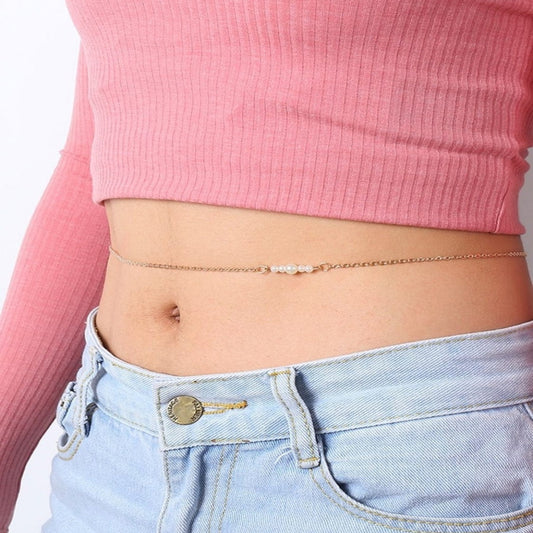 Person wearing a pink top and light blue jeans with a gold chain around their waist.