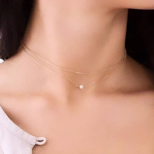 Gold necklace with a pearl pendant worn by a person