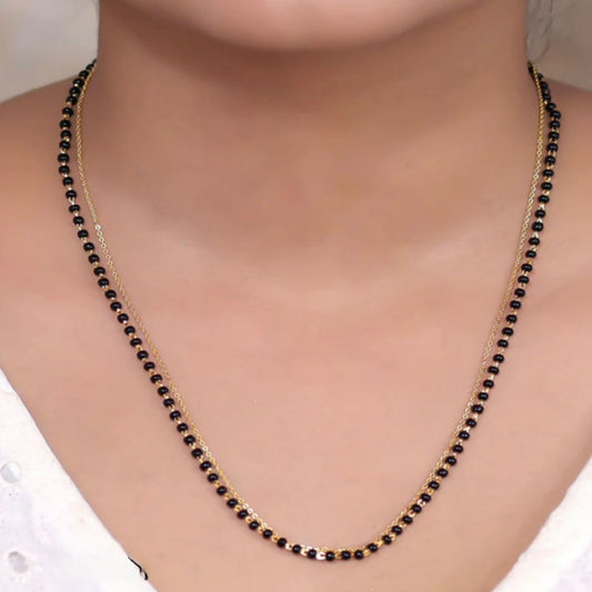 Necklace with black beads on a person wearing a white top
