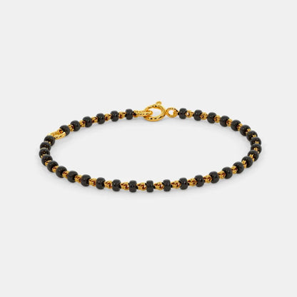 Black beaded bracelet with gold clasp on a white background