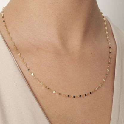 Gold necklace on a person's neck with a neutral background