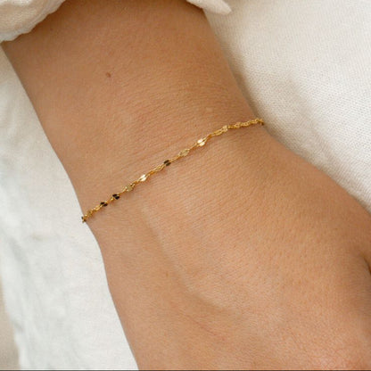 Gold anklet on a person's ankle with a light background