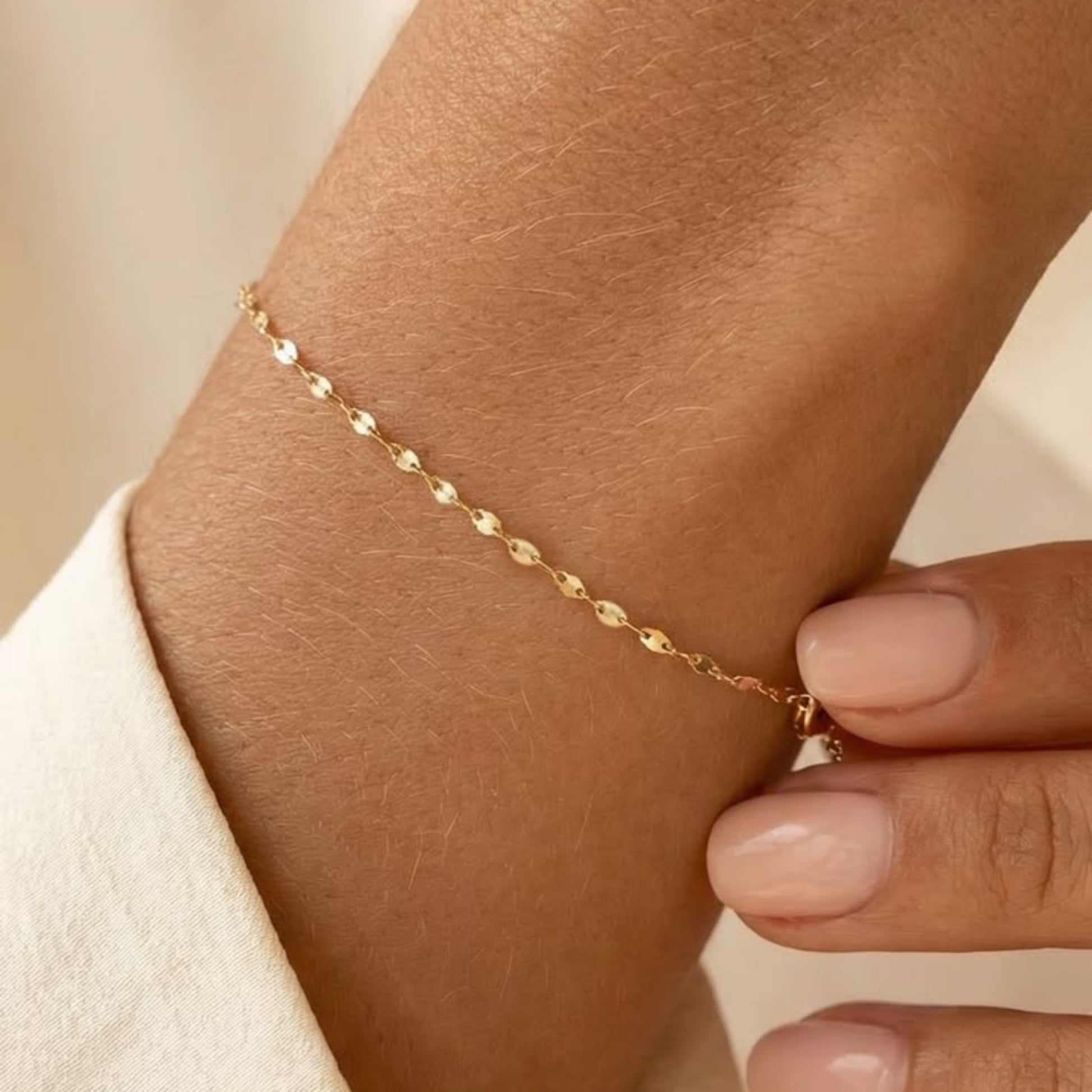 Gold bracelet on a wrist with a neutral background