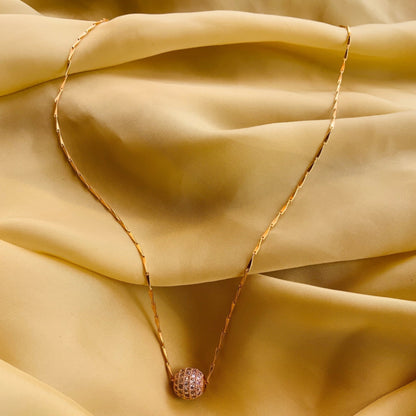 Gold necklace with a pink pendant on a beige fabric background
