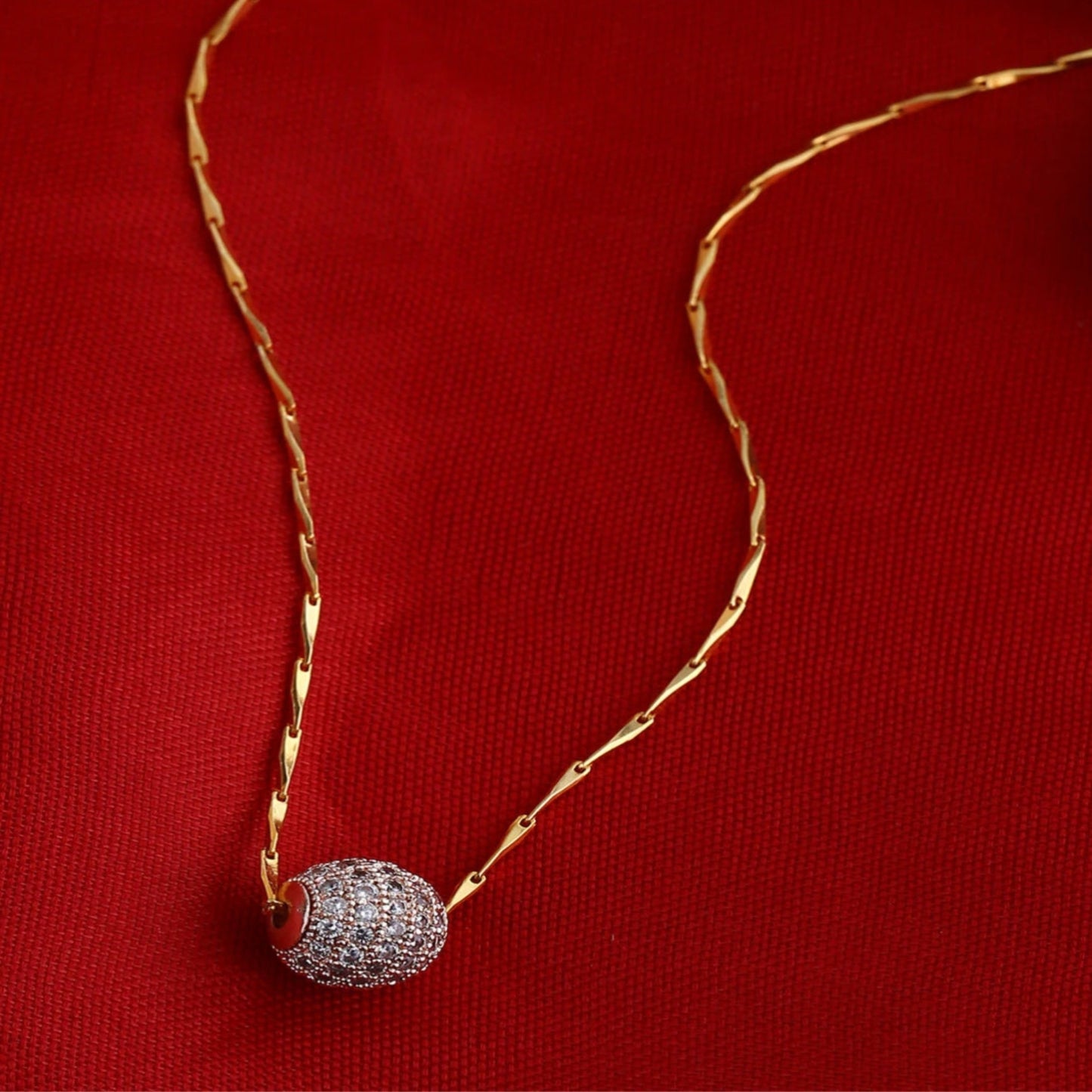 Gold necklace with a diamond pendant on a red background