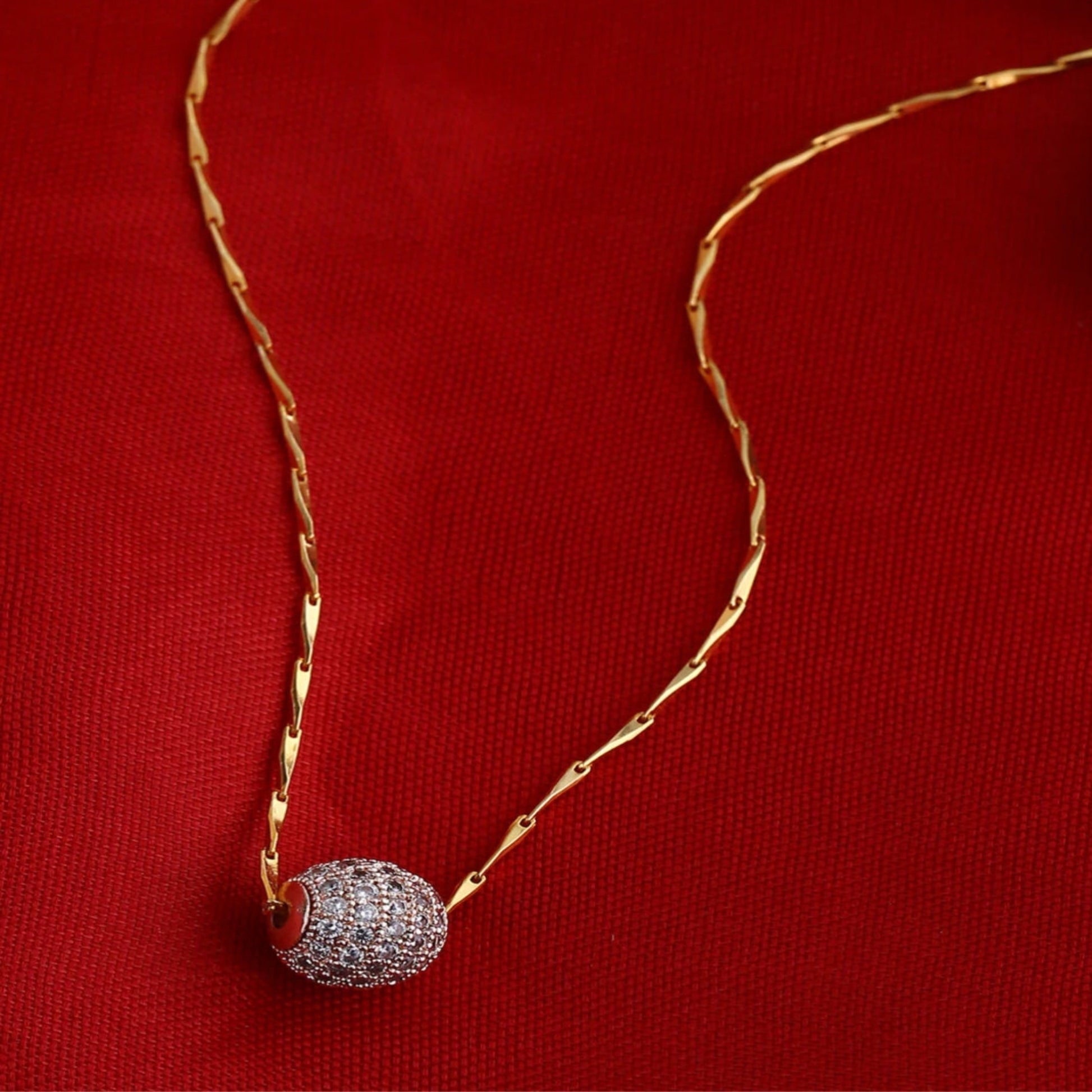 Gold necklace with a diamond pendant on a red background