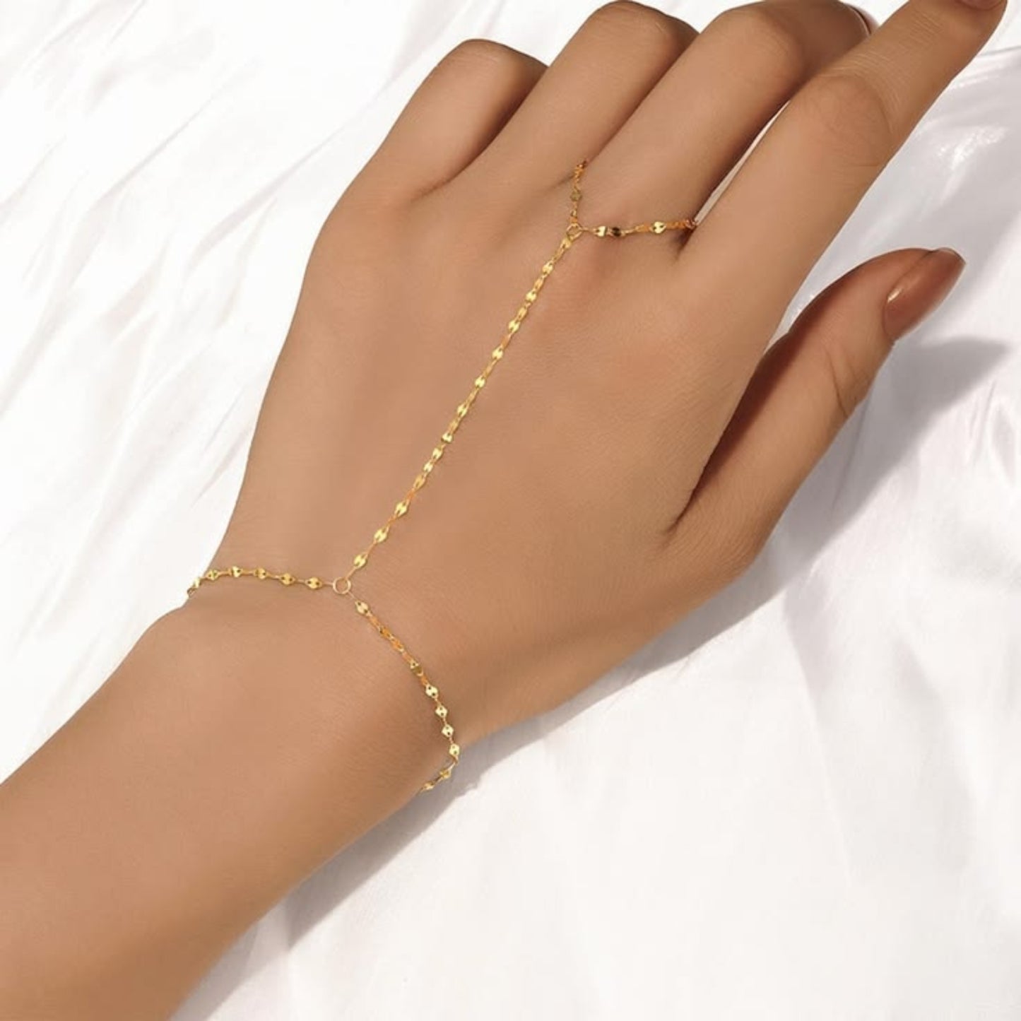 Gold hand chain on a hand against a white background