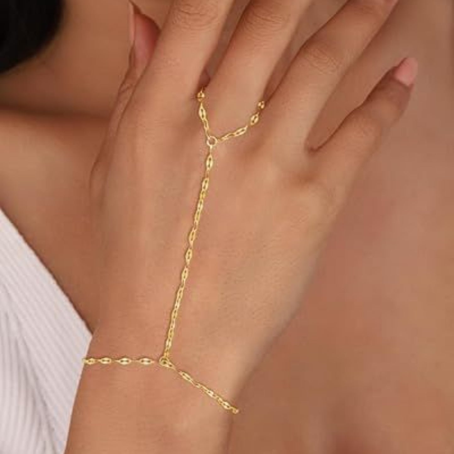 Gold body chain worn on a hand with a blurred background