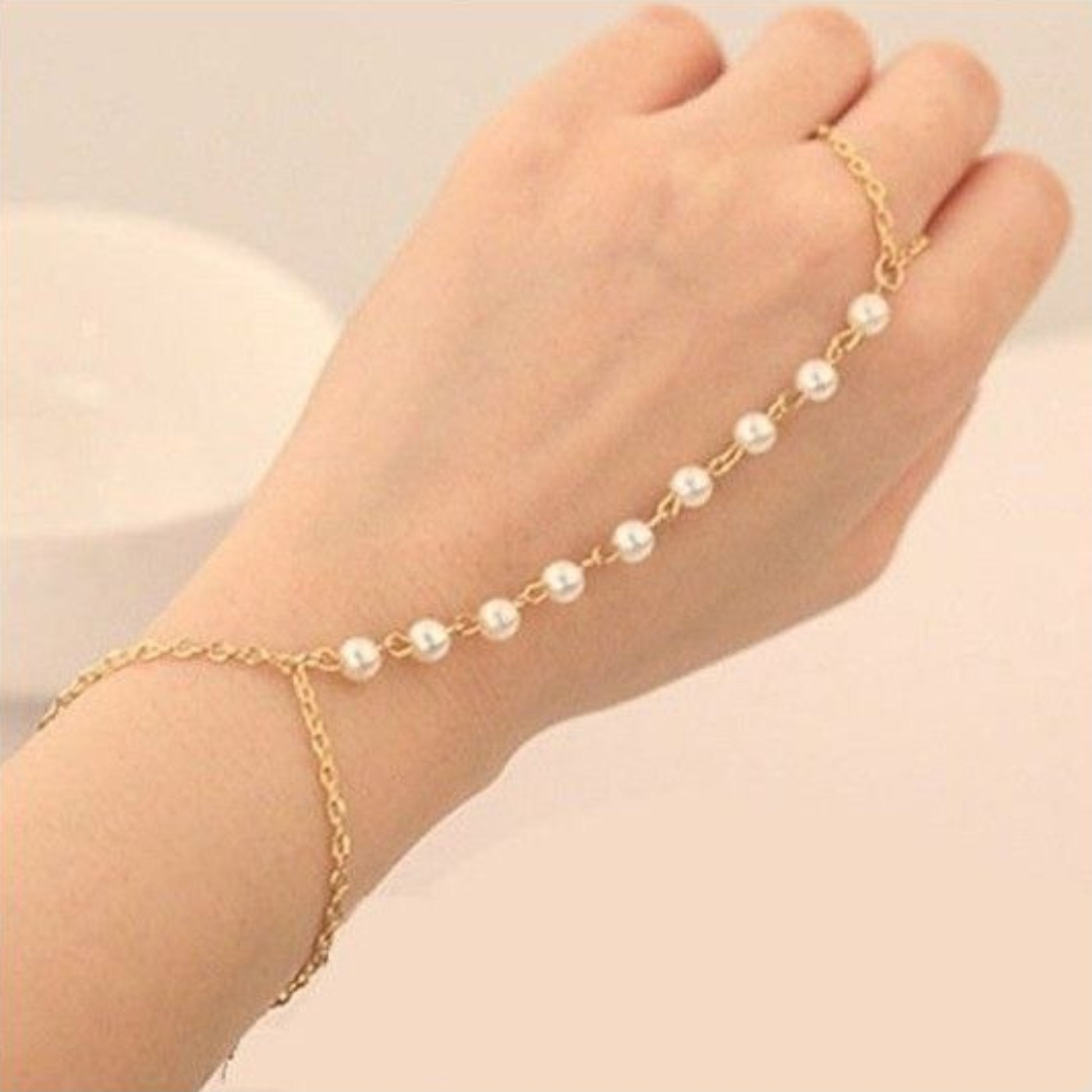 Gold anklet with pearls on a foot against a beige background