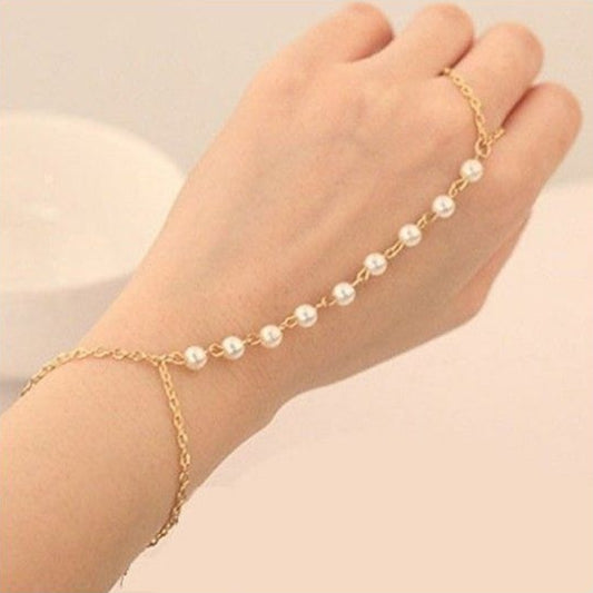 Gold anklet with pearls on a foot against a beige background